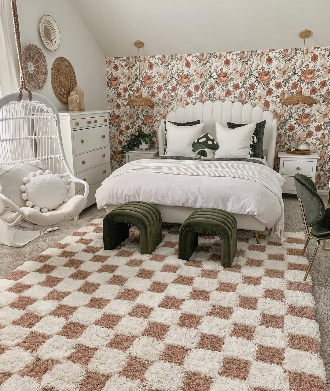 Teen girl bedroom featuring a floral accent wall, white bed with green pillows, two green stools, a checkered rug, and a hanging chair beside a white dresser.