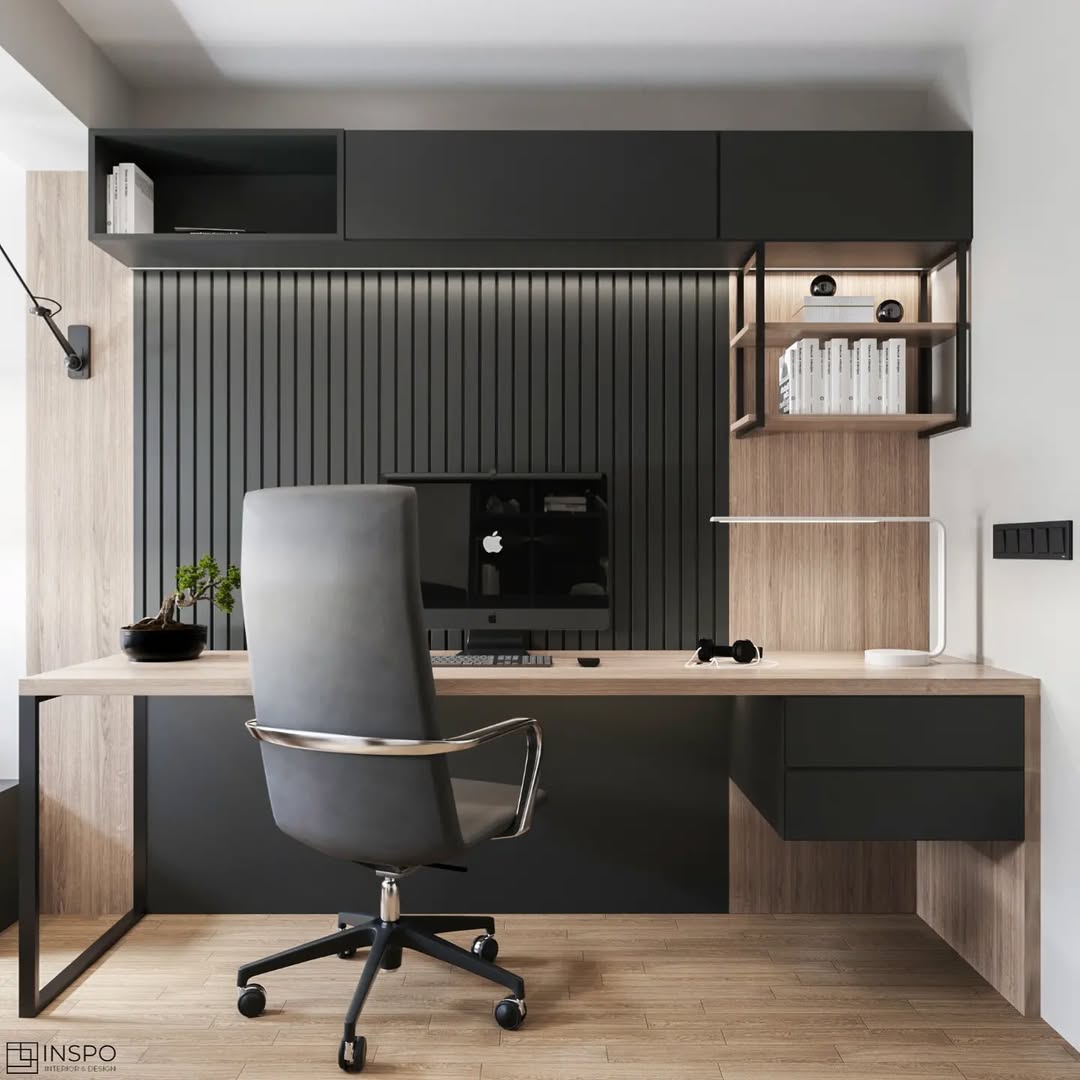 Modern small home office with a black desk, white chair, desk lamp, and books. Black shelf with vases and books on the wall and three abstract black-and-white art prints above.