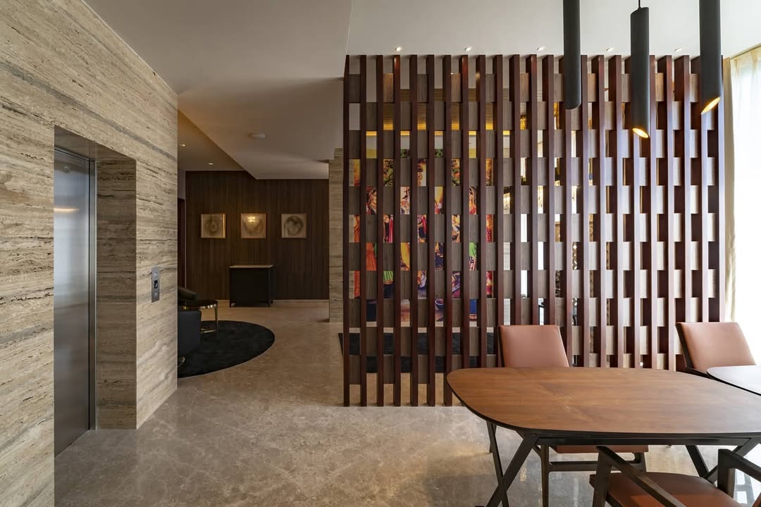 Modern office lobby with marble floors, a stainless steel elevator, and a decorative wood partition—perfect for instant style inspiration and divider screen ideas among contemporary furniture near large windows.
