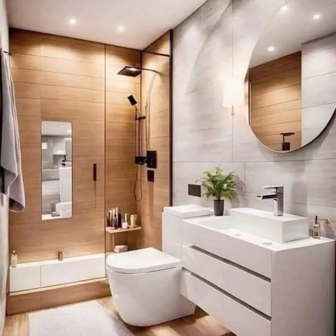 Modern bathroom with wood and white decor, glass shower enclosure, wall-mounted toilet, large round mirror, white vanity, potted plant, and recessed lighting—perfect inspiration for Small Bathroom Design or creative Half Bathroom Ideas.