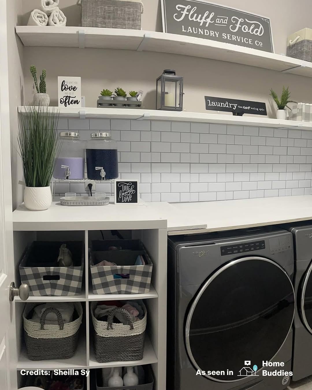Modern laundry room with front-loading washer and dryer, sleek laundry room shelves, decorative signs, small plants, and organized storage baskets.
