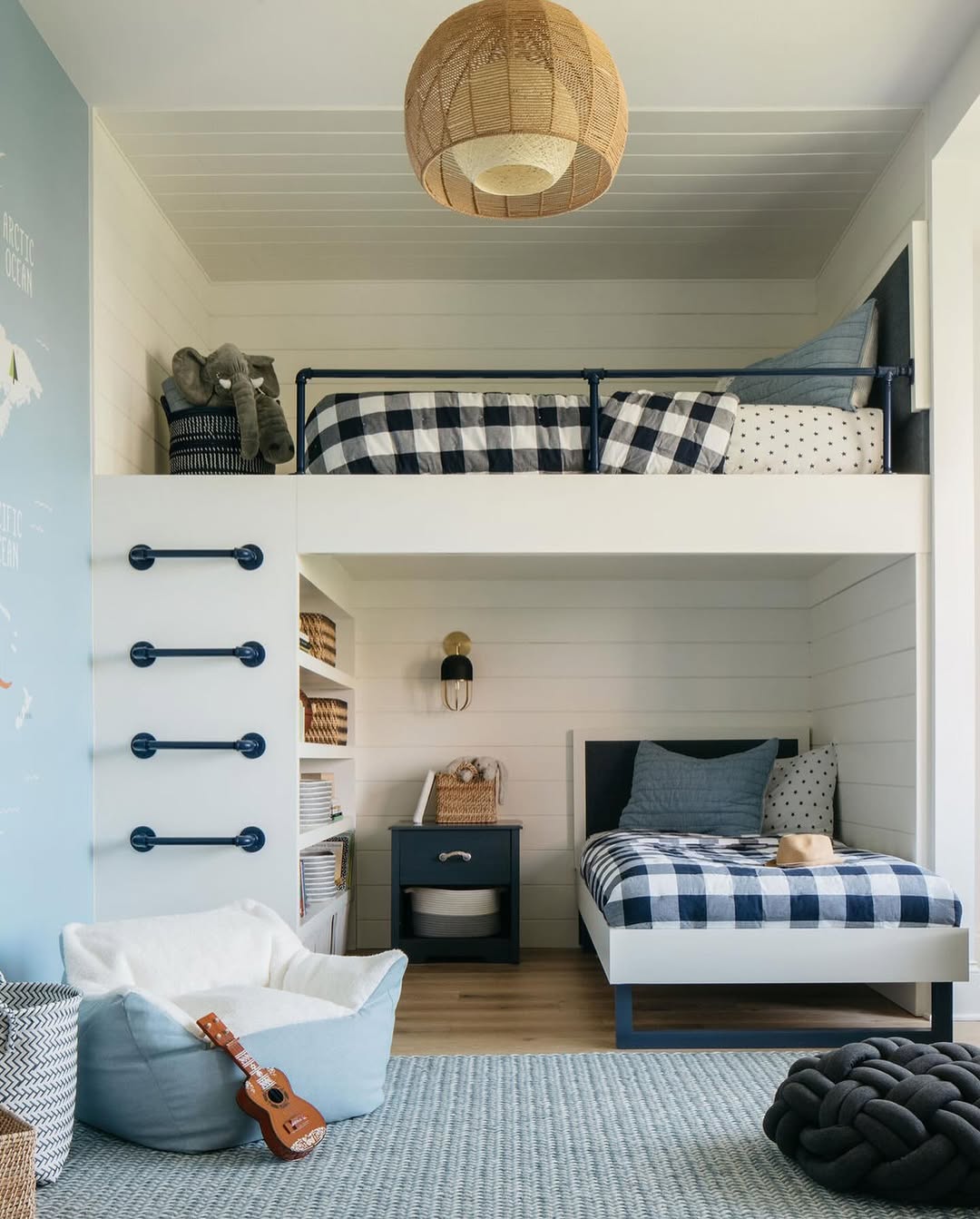A modern children's bedroom features a loft bed for small room designs, plaid bedding, wall-mounted ladder, cozy bean bag, small guitar, and woven ceiling light. Shelves display baskets and folded clothes for a tidy look.
