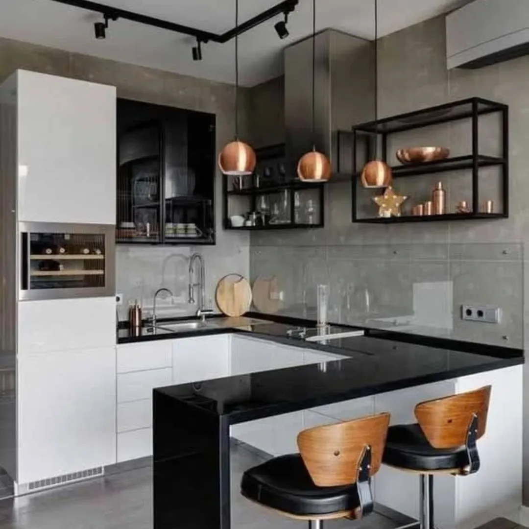 Modern kitchen with black and white cabinets, black countertops, open shelves, copper pendant lights, and two wooden bar stools at the counter.