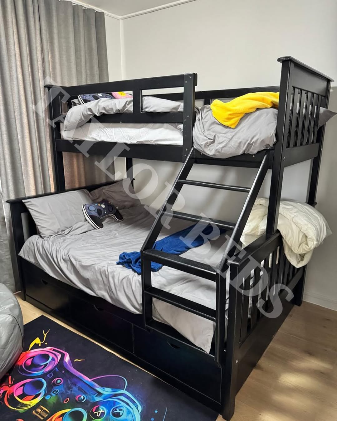 A black wooden loft bed for small room features a double bed below and a single bed above, with gray and yellow bedding and an easy-access ladder.