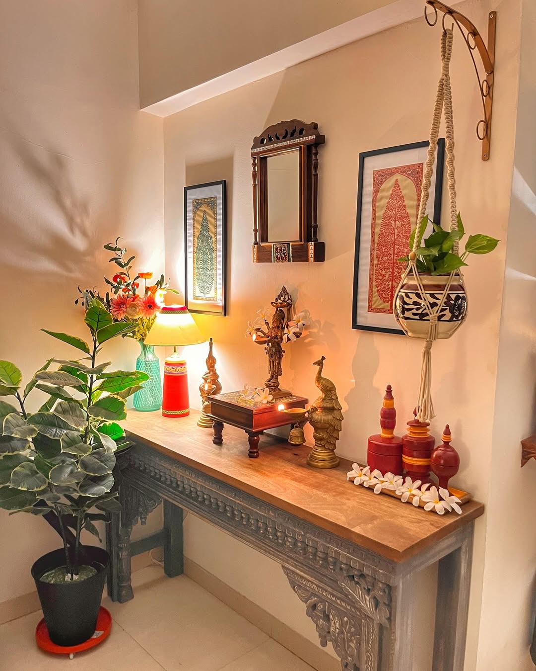 A decorated entry table features lamps, statues, framed art, a mirror, potted plants, and decorative objects arranged in a well-lit corner of the room for stylish entry table decor.