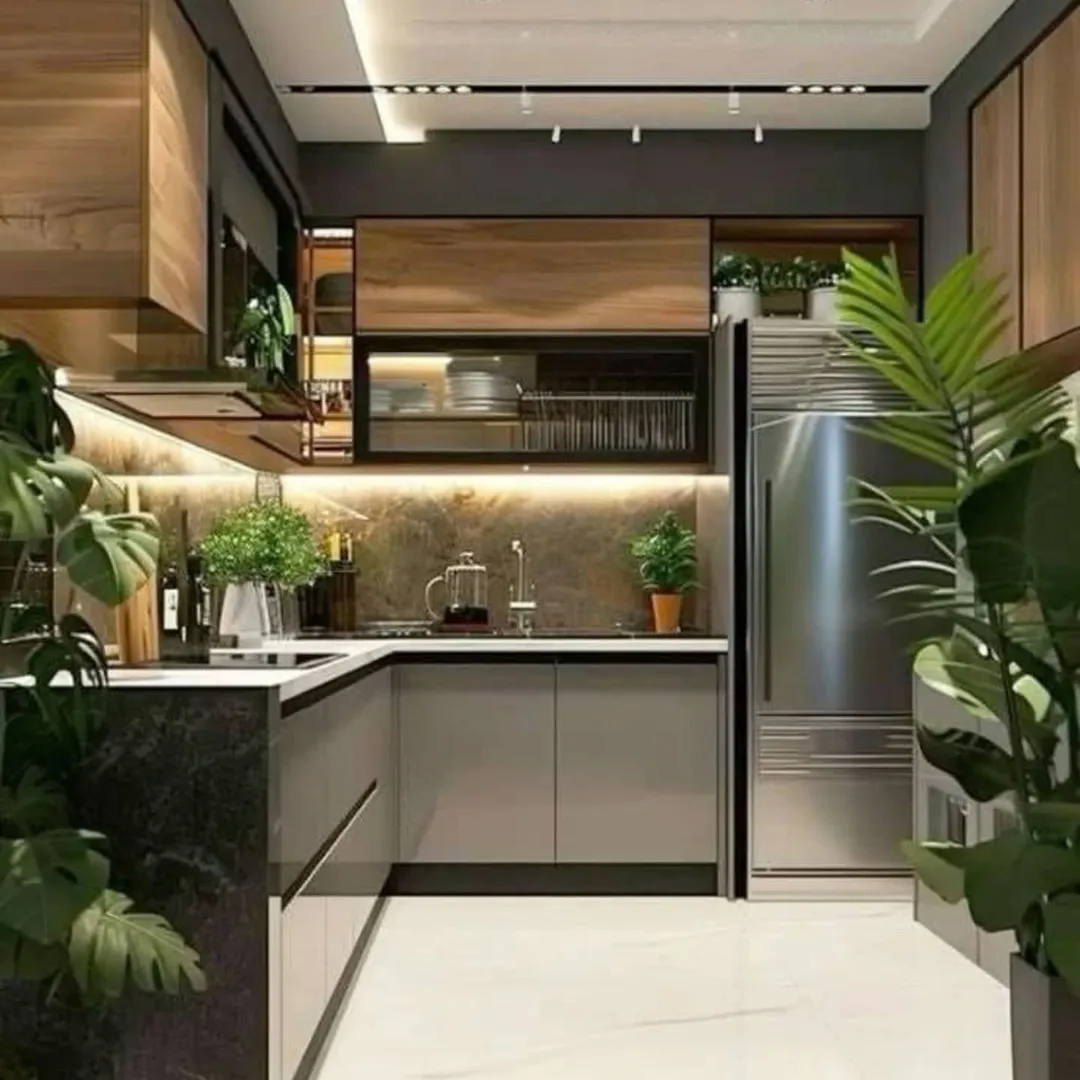Modern kitchen with stainless steel refrigerator, wooden cabinets, under-cabinet lighting, and several green potted plants on counters and floor.
