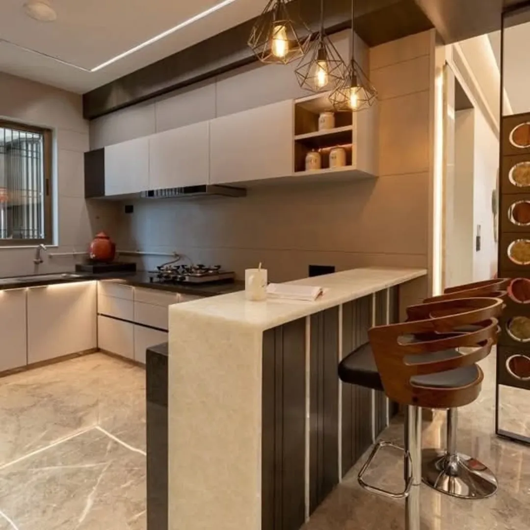 Modern kitchen with beige cabinets, marble flooring, a breakfast bar with three bar stools, pendant lights, and a window above the sink.