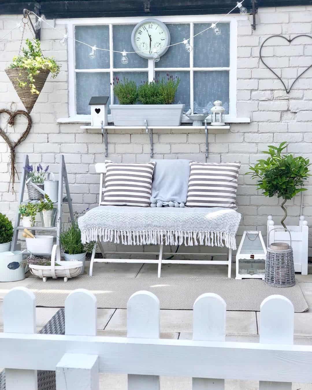 Grey Wall Clock Above White Garden Bench