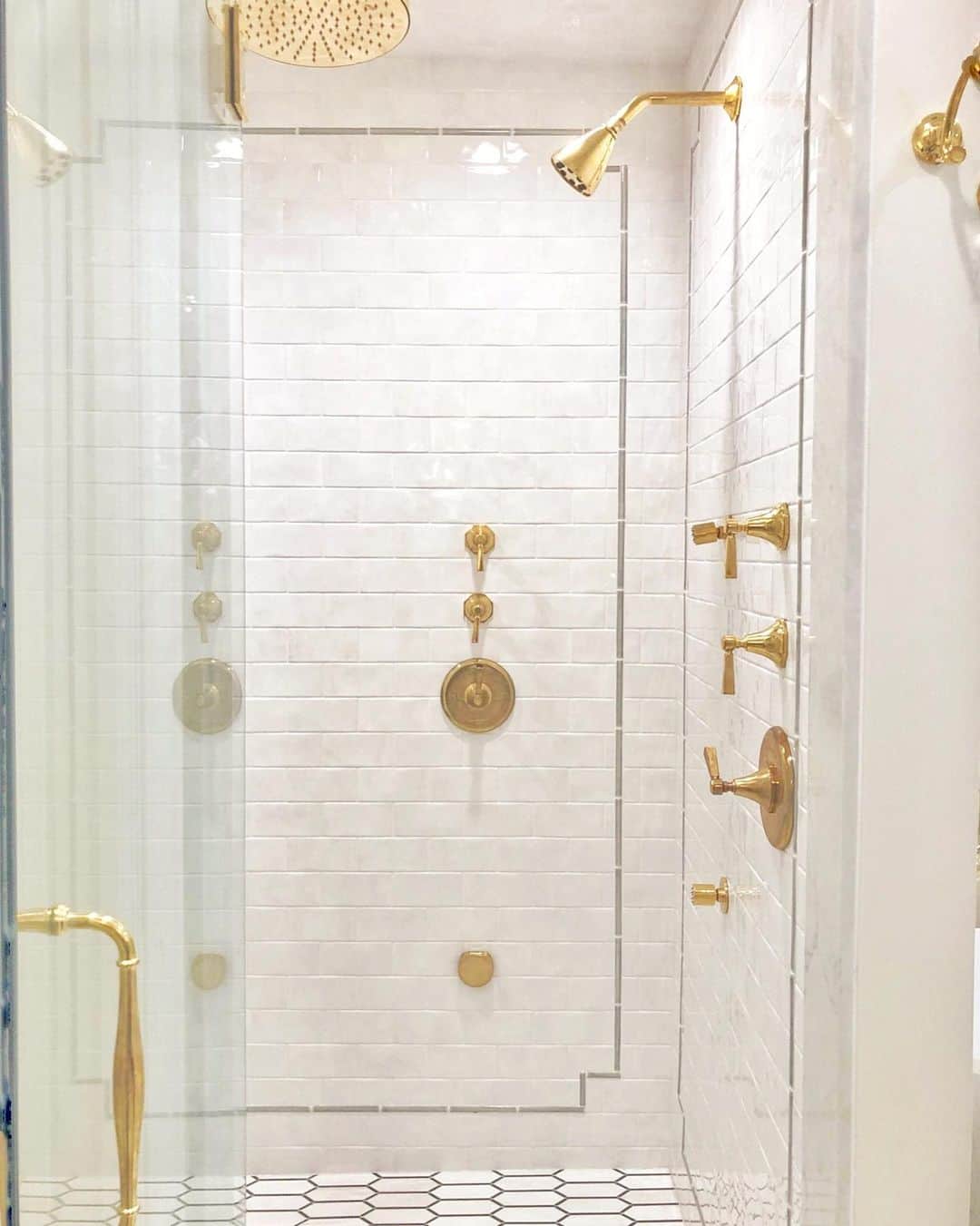 Polished Brass Shower Head on a White Tile Wall